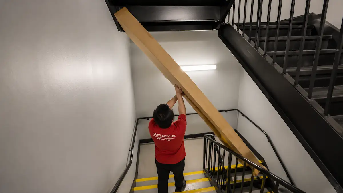 Professional movers carrying a long item through a condo stairwell in North York.
