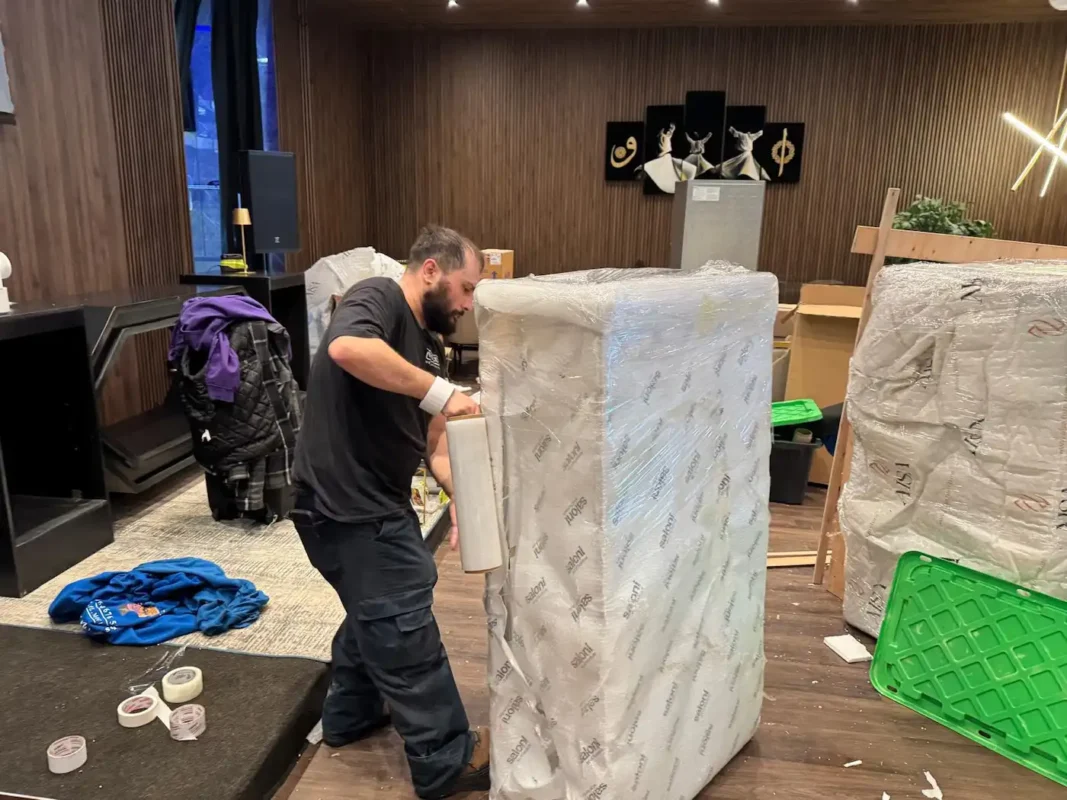 Professional movers wrapping furniture with protective stretch film before a move in commercial moving North York