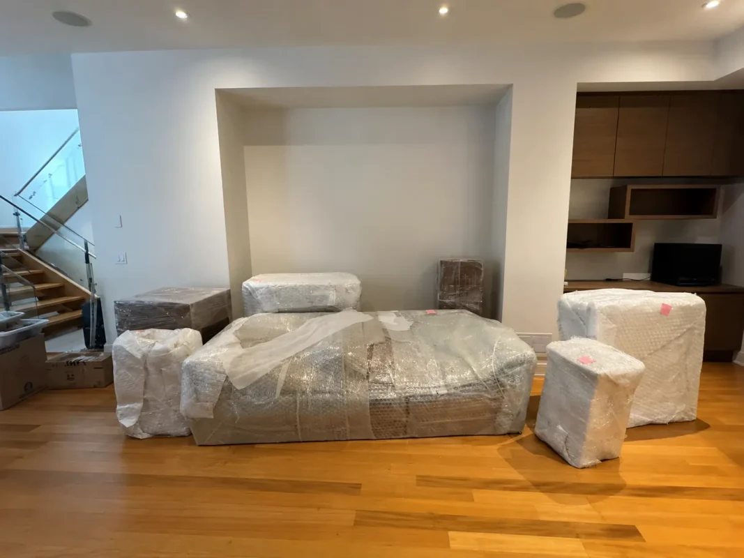 Professional movers wrapping furniture with protective bubble wrap before a residential move in Mississauga.